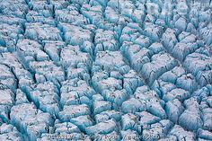 an aerial view of ice formations in the arctic with blue hues and snow on them