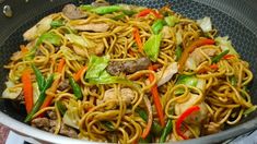 stir fried noodles with vegetables and meat in a frying pan