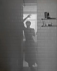 a man standing in front of a shower with his hand up to the side and arms outstretched