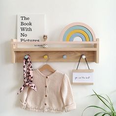 a wooden shelf with a book, hat and scarf on it next to a potted plant