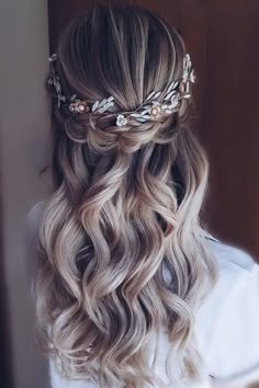 the back of a woman's head with long wavy hair and flowers in her hair