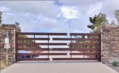 an image of a gate that is in the middle of a driveway with stone walls