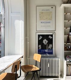 two chairs are sitting in front of a book shelf with books on it and a radiator