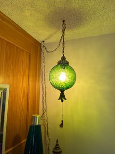 a green lamp hanging from the ceiling next to a mirror