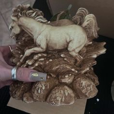 a hand holding a small statue of a horse