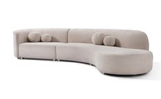 the curved sofa has four pillows on it's back and is made from fabric