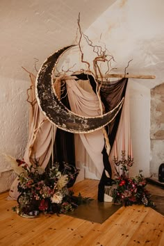 the moon is hanging from the ceiling in front of some flowers and plants on the floor