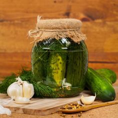 cucumbers and garlic sit in a jar on a cutting board