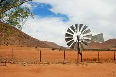 a windmill sitting in the middle of a dirt field