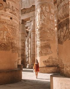 a woman is walking through an ancient building