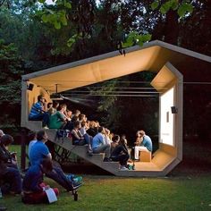 people are sitting on the steps in an open air area with trees and grass behind them