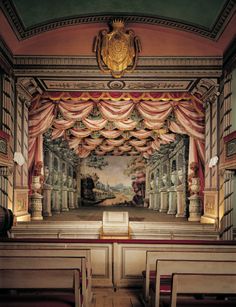 an empty church with the stage decorated in red and white drapes, gold crown above it