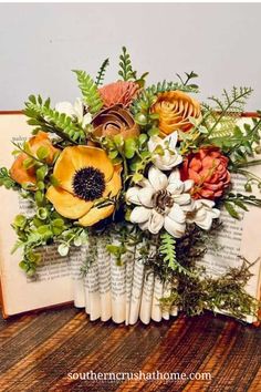 an open book with flowers and greenery on it