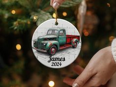 a hand holding a christmas ornament with an image of a truck on it