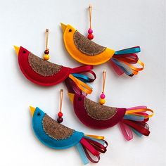 three colorful bird ornaments hanging from strings