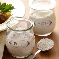 three jars filled with food sitting on top of a table next to two spoons