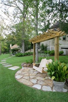 a wooden bench sitting in the middle of a lush green yard next to a tree