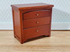 a small wooden dresser sitting on top of a hard wood floor next to a wall