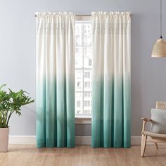 a living room with a chair, window curtain and potted plant