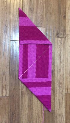 a pink and purple kite laying on top of a wooden floor