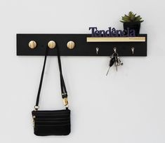 there is a key rack with two keys and a purse hanging on the wall next to it