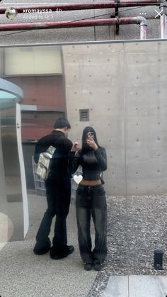 a man and woman standing in front of a mirror with their reflection on the wall