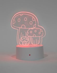 an illuminated mushroom lamp with a cat on it's head in front of a gray background