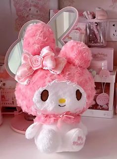 a pink hello kitty stuffed animal sitting on top of a desk next to a mirror