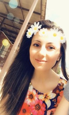 a woman with long hair and flowers in her hair is smiling at the camera while standing outside