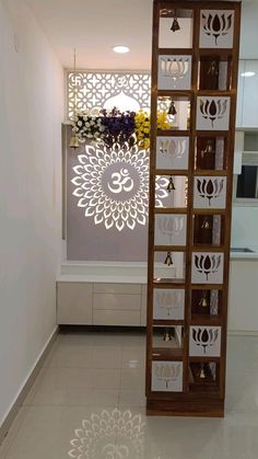 a tall wooden shelf sitting inside of a room next to a flower vase on top of a tiled floor