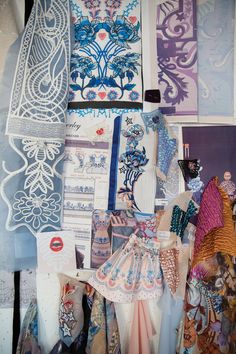 many different types of fabric and patterns on display in a shop window, some with laces