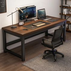 a computer desk with a laptop on top of it next to a chair and bookshelf