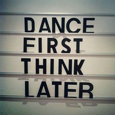 the words dance first, think later are written in black and white on a wall