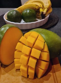 sliced mangoes, limes and bananas on a cutting board with a bowl of fruit in the background