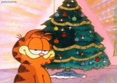 garfield the cat standing in front of a christmas tree