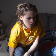 a young woman sitting on top of a bed holding a nintendo wii game controller in her hand