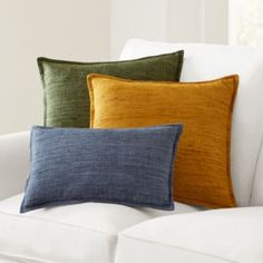 three pillows sitting on top of a white couch