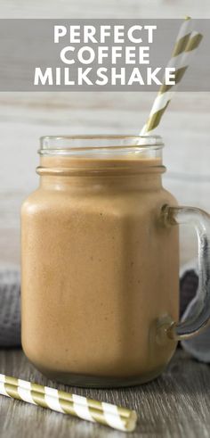 a glass jar filled with coffee milkshake on top of a wooden table next to two straws