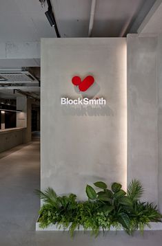 an office building with a sign that says black smith on the wall and plants in front of it