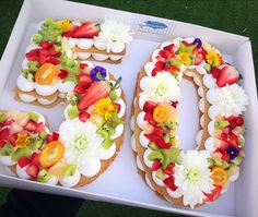 the number 50 decorated with fresh fruit and flowers is displayed in a white box on grass