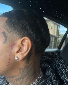 a man with tattoos on his face sitting in a car