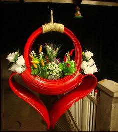 a red heart shaped planter with white flowers and greenery hanging from it's side