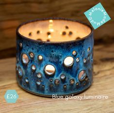 a blue candle holder sitting on top of a wooden table next to a lit candle