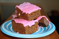 three pieces of cake sitting on top of a blue and white plate with pink frosting