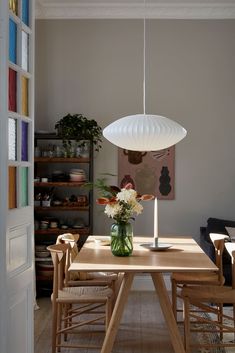 a dining room table with chairs and a vase filled with flowers on top of it