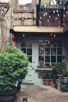 an old building with potted plants in front of the door and on the outside