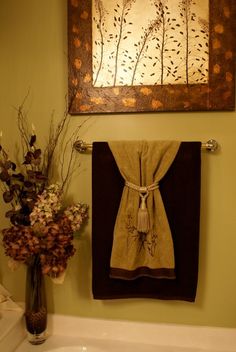 a bathroom with towels hanging on the wall and flowers in vase next to the sink