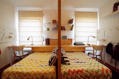 a bed room with a neatly made bed and two desks next to each other