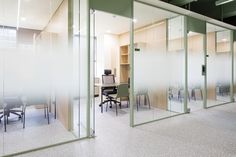 an office with glass partitions and chairs in it's cubicle area,