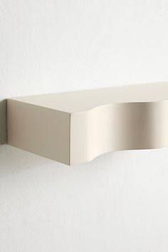 a white wall mounted shelf sitting on the side of a wall